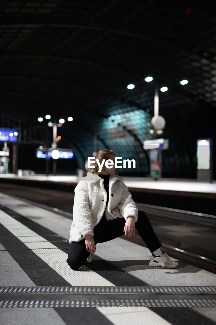 Woman standing on railroad station platform at night