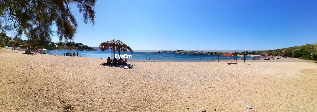 TOURISTS ON BEACH AGAINST CLEAR SKY