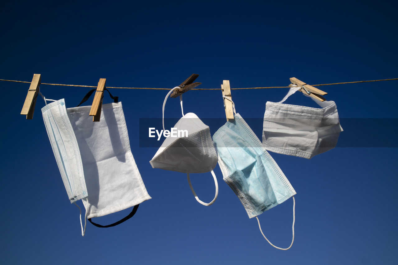 Low angle view of clothes hanging on clothesline against blue sky