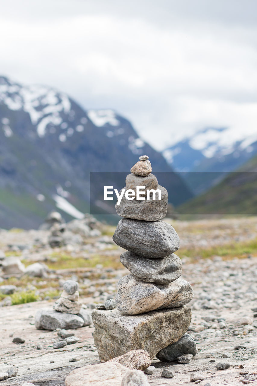 Stack of stones on rock against sky and mountains 