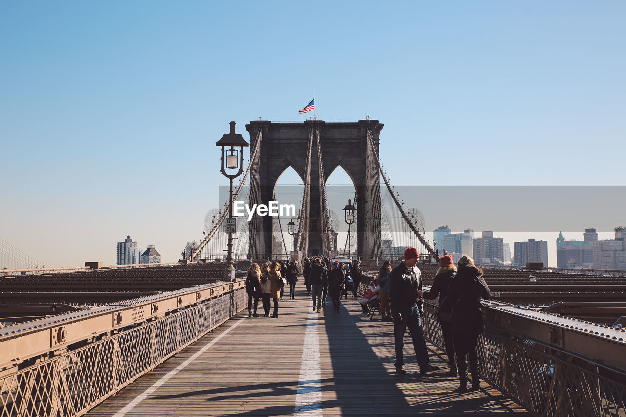 PEOPLE ON SUSPENSION BRIDGE AGAINST SKY