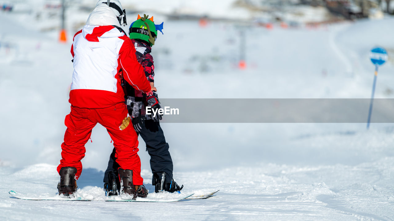 Boy learning snowboarding with an instructor