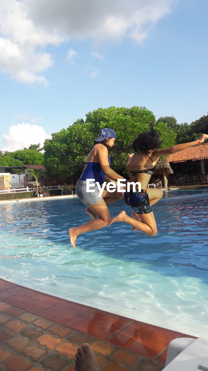 FRIENDS ENJOYING IN SWIMMING POOL