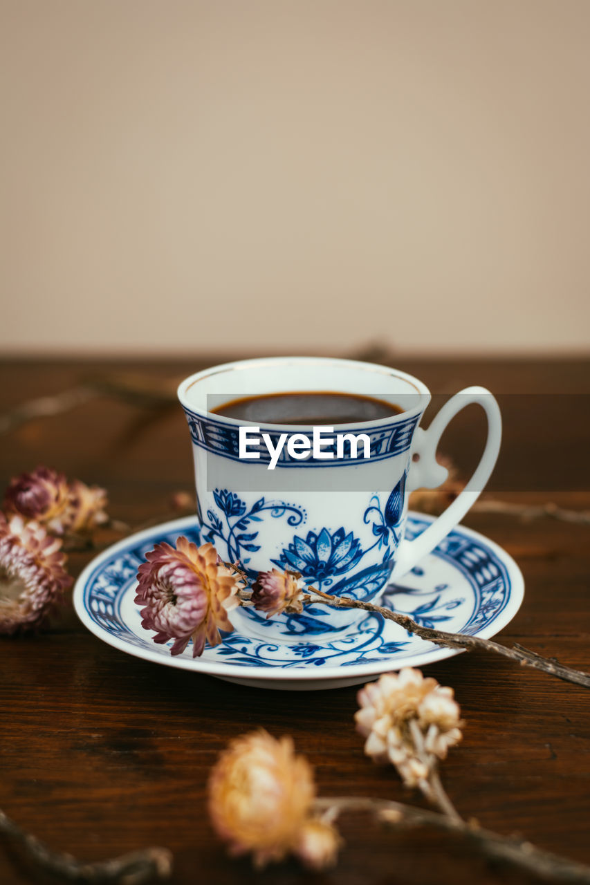 CLOSE-UP OF TEA CUP ON TABLE AGAINST WALL