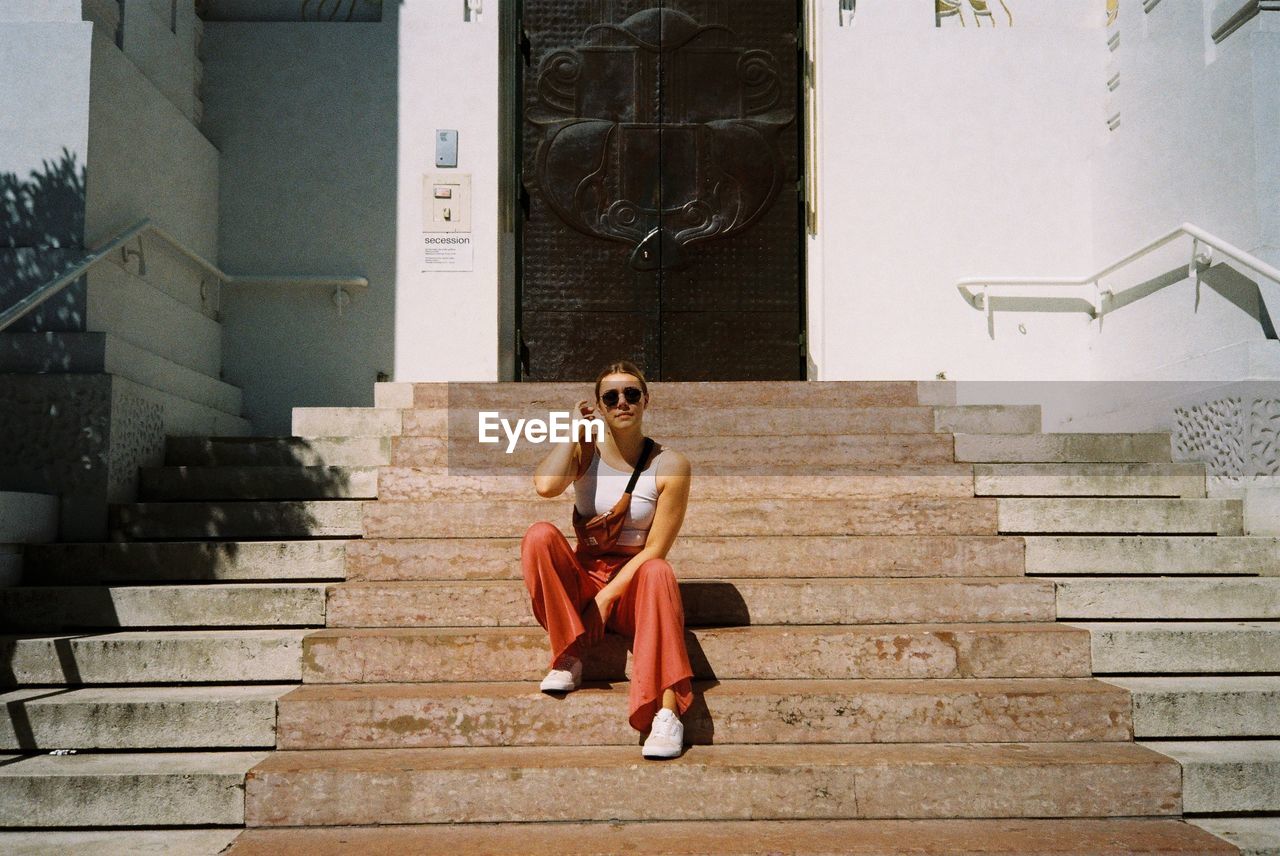 YOUNG WOMAN SITTING ON STAIRCASE