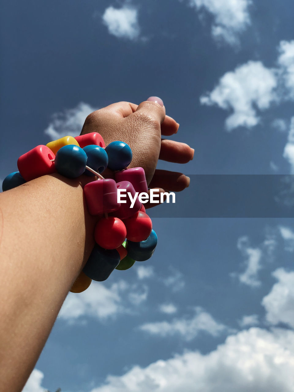 Close-up of hand holding multi colored against sky