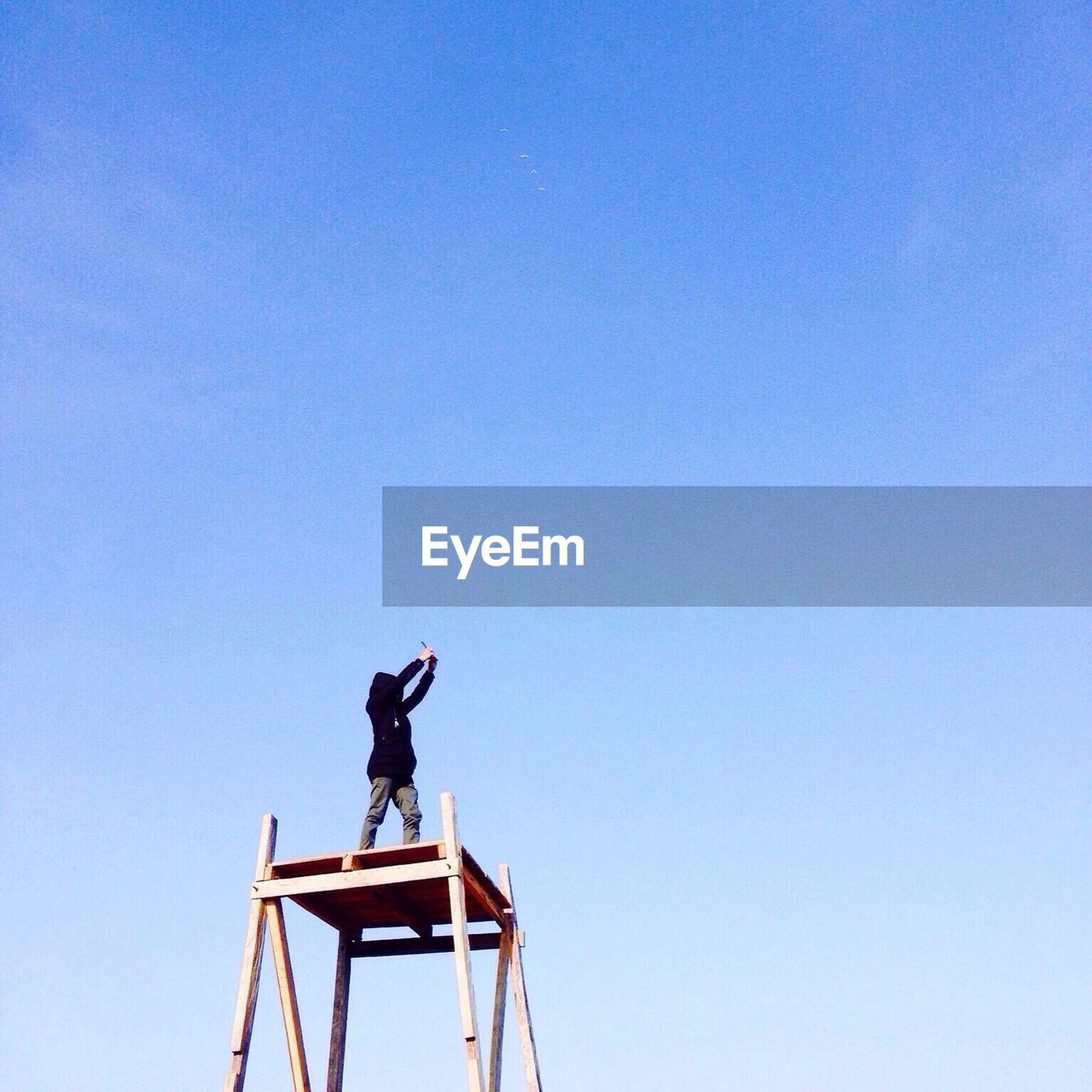 Low angle view of person on lookout tower taking picture with camera