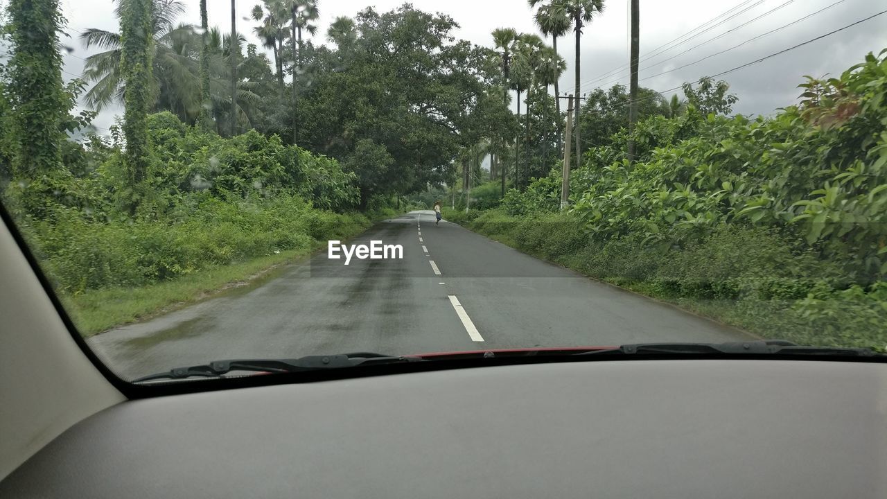 ROAD AMIDST TREES AGAINST SKY SEEN FROM CAR WINDSHIELD