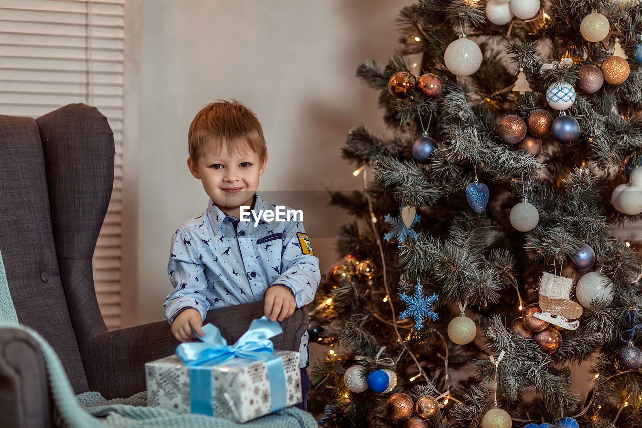 BOY WITH CHRISTMAS TREE AT HOME