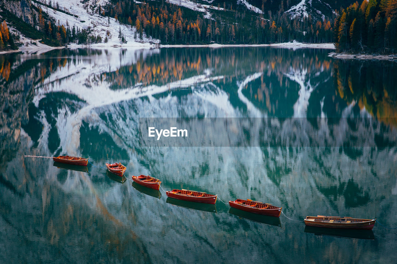 Boats in lake against snowcapped mountains