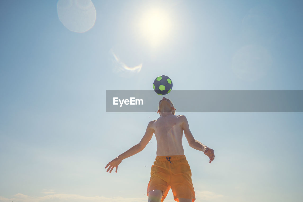 Low angle view of man playing with ball against sky