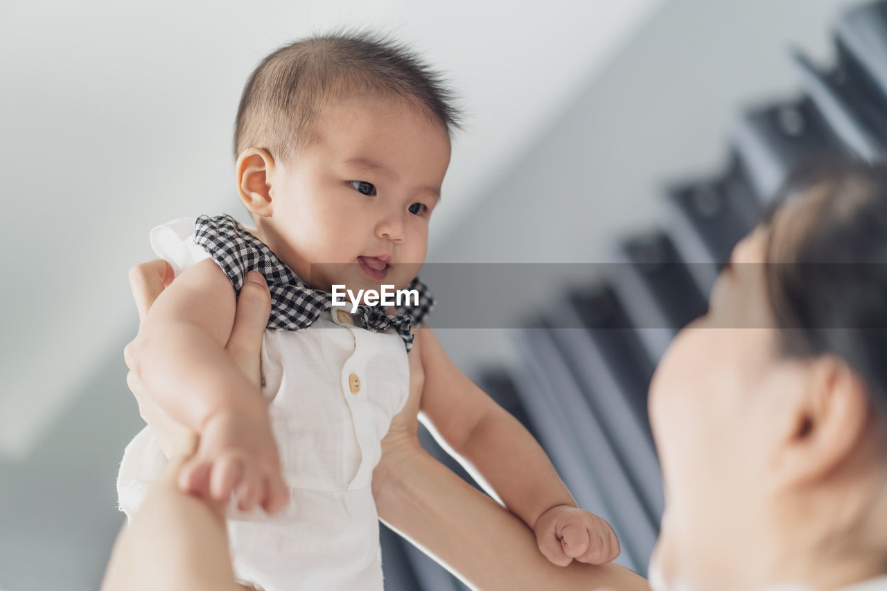 side view of mother carrying daughter at home