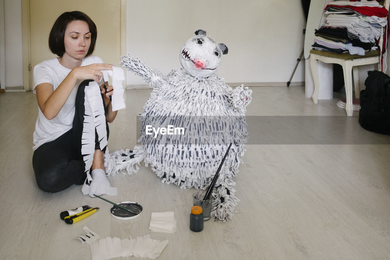 Woman making stuffed toy sitting at home
