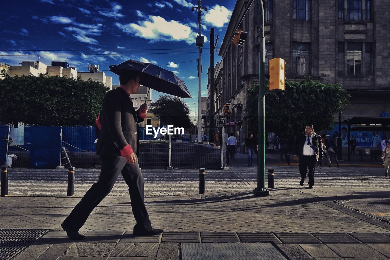 PEOPLE WALKING ON FOOTPATH BY CITY STREET