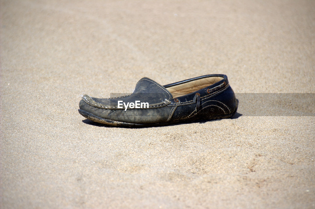 Close-up of shoe on sandy beach