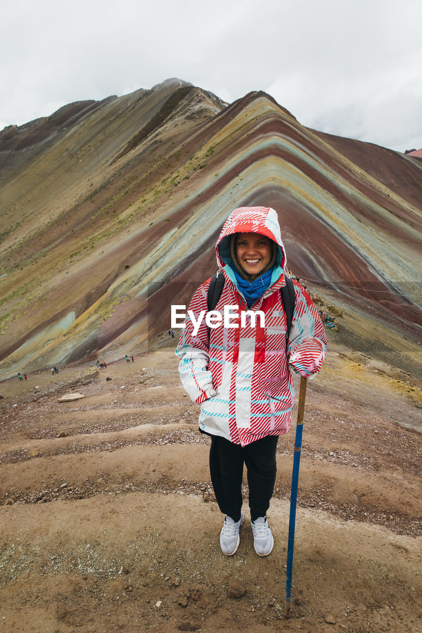 A young woman is standing on the famous rainbow mountain in peru