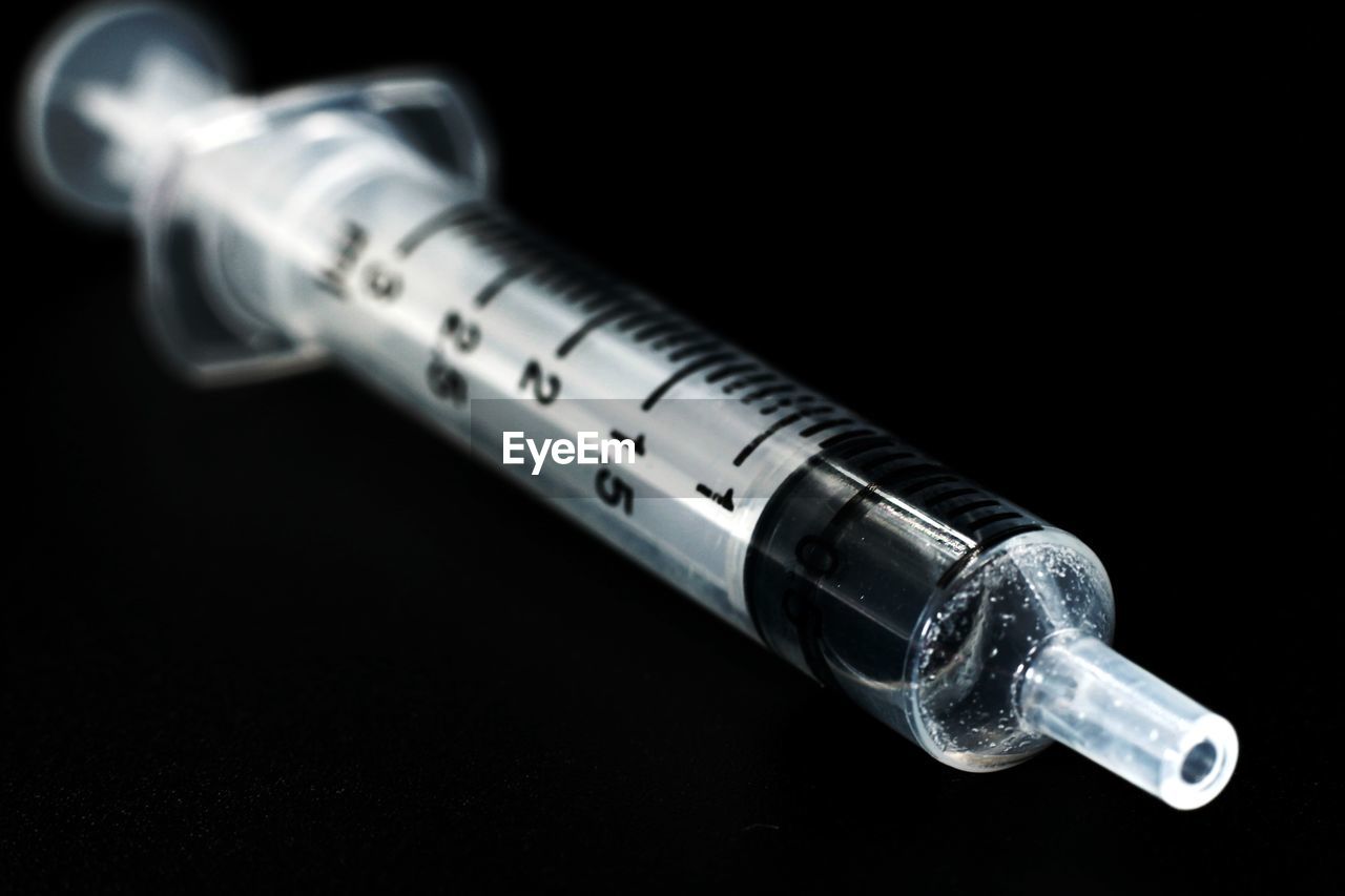 Close-up of syringe on black background