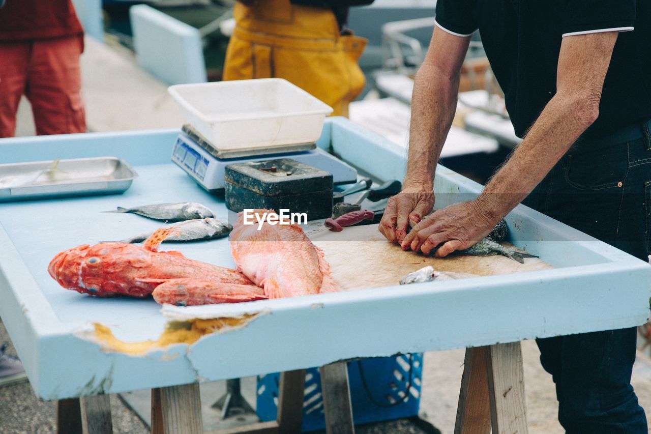 Man slicing fishes at market stall