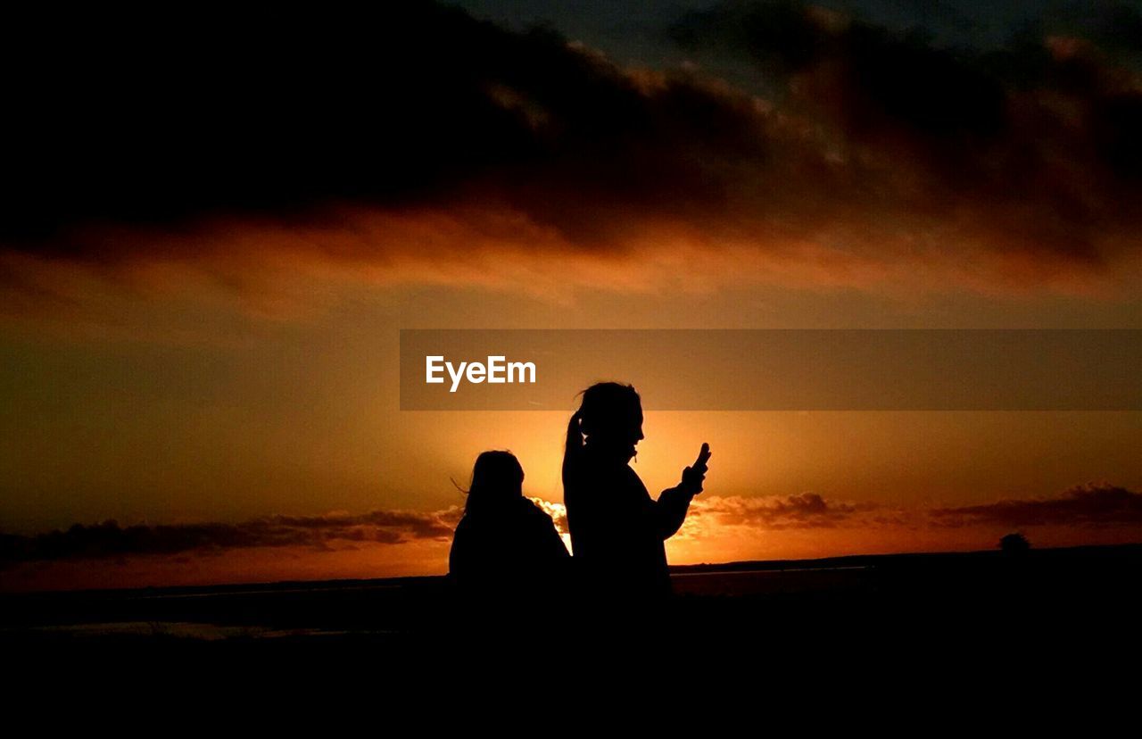 Silhouette women against sky during sunset