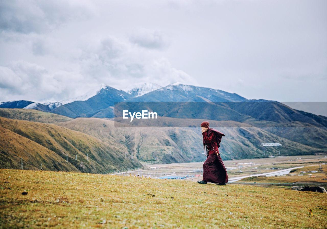 WOMAN STANDING ON MOUNTAIN AGAINST SKY