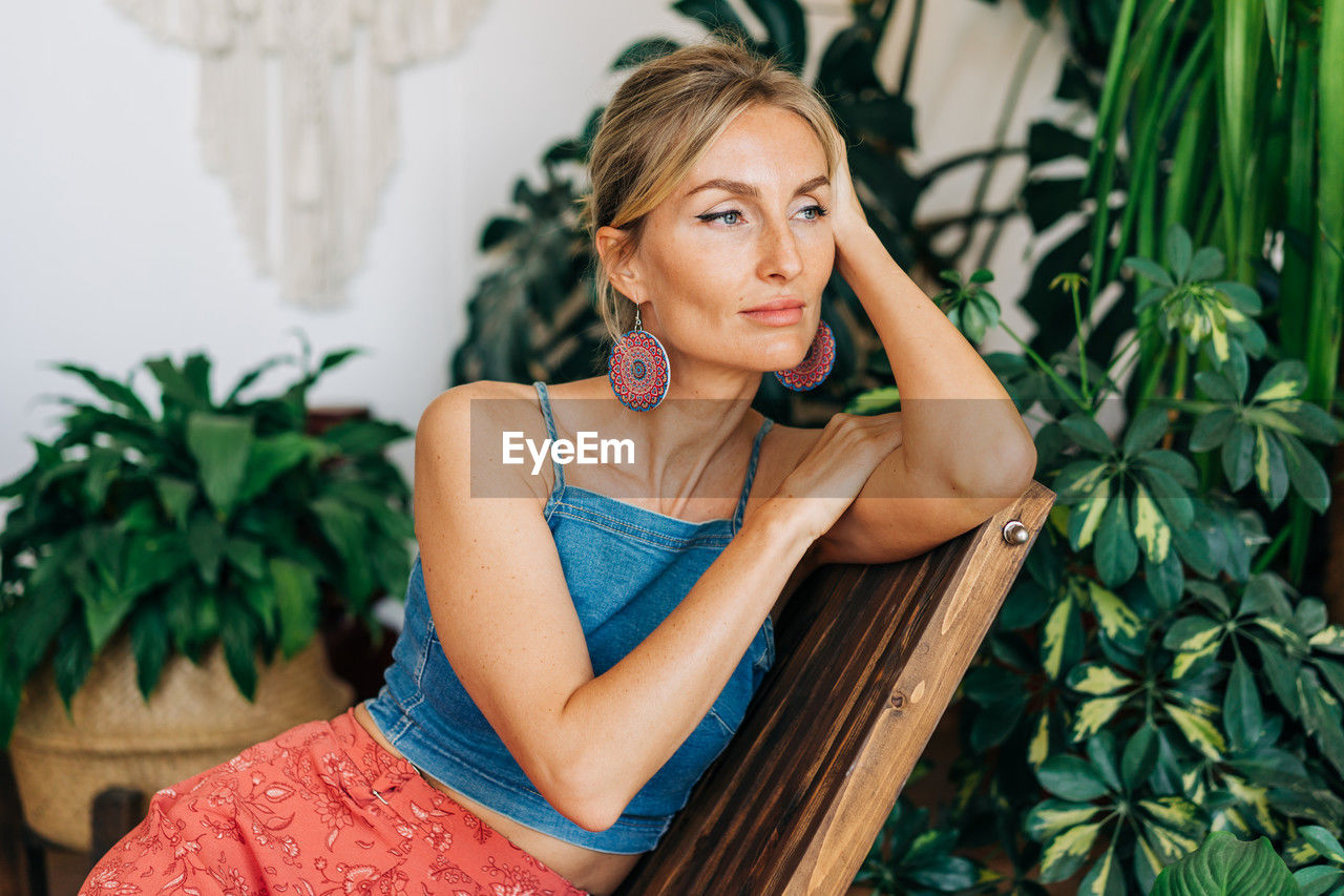 Portrait of a young attractive woman sitting in a chair in a flower studio.