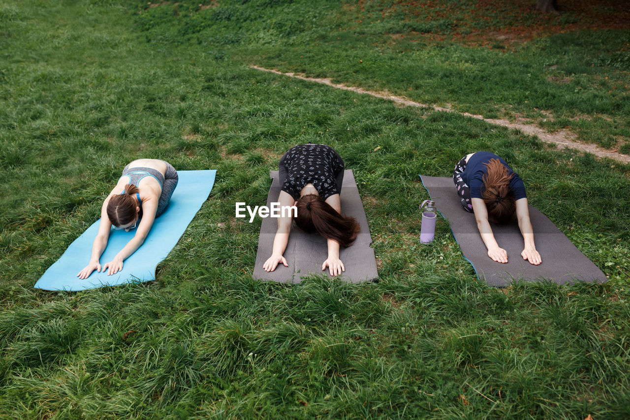 The relaxed girls is doing yoga in the park on carpet