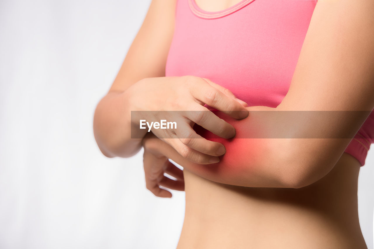 Midsection of woman with hand pain over white background