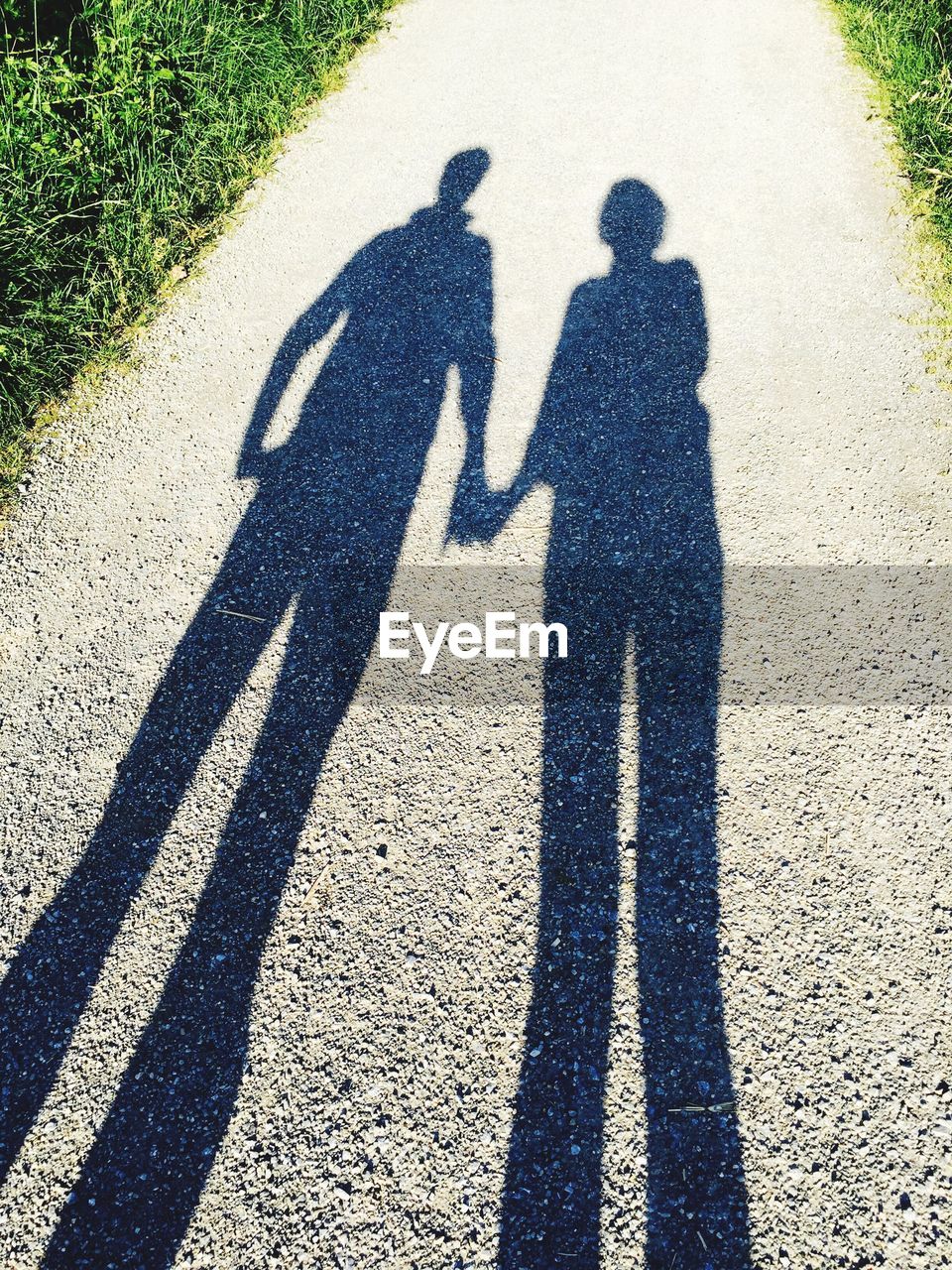 High angle view of couple shadow on dirt road