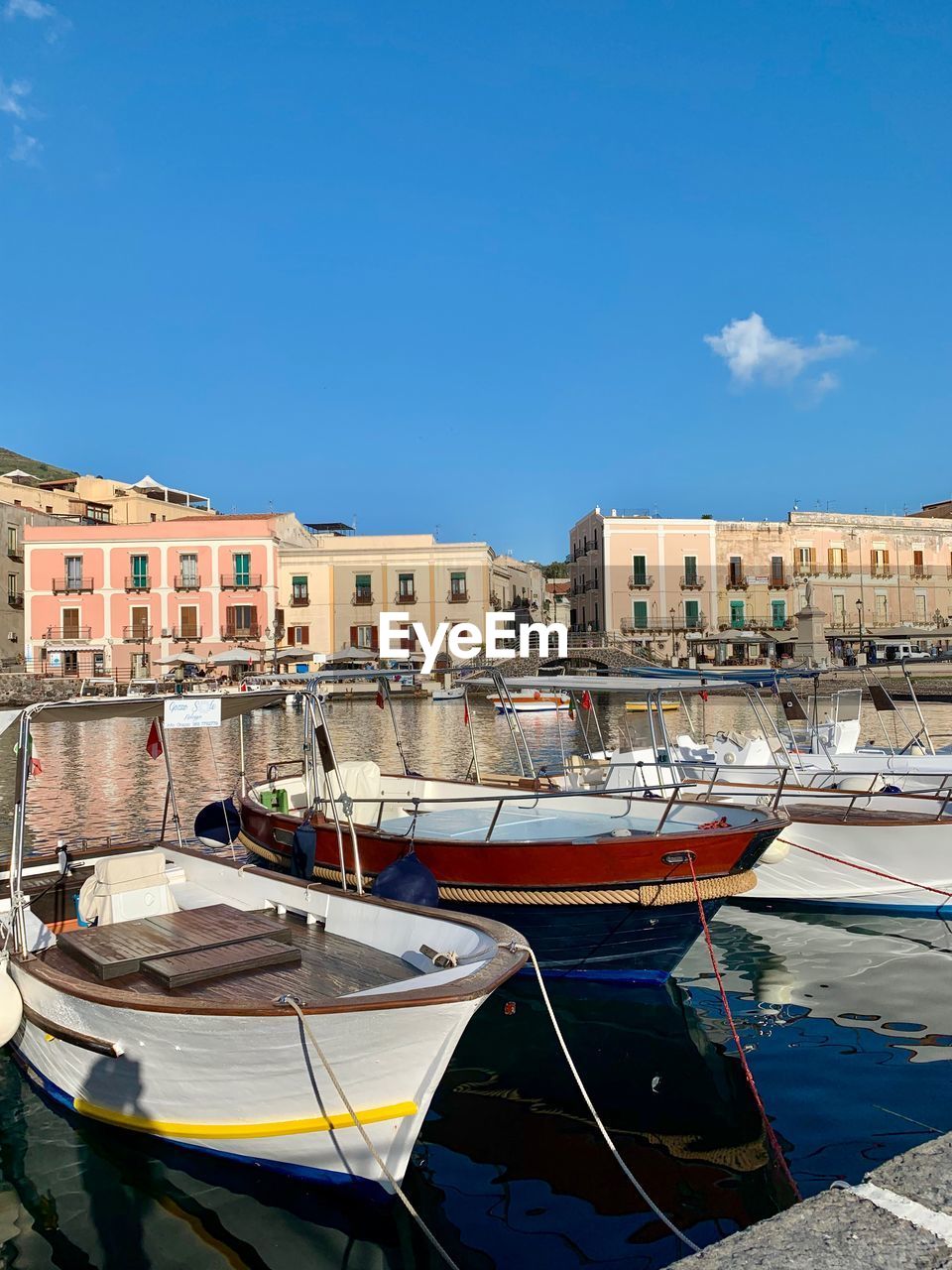 Sailboats moored at harbor against buildings in city