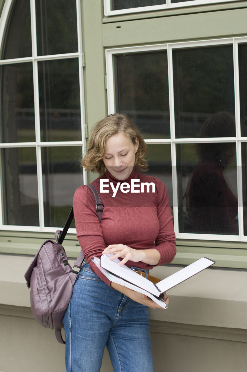 Young caucasian girl going back to college, school, standing with a notebooks