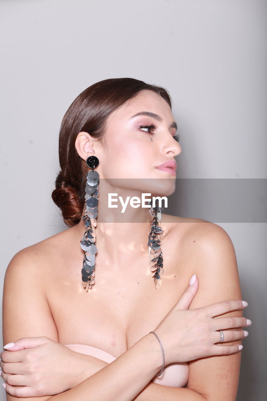 High end fashion  head shot of brunette model wearing long shiny earrings, professional make up