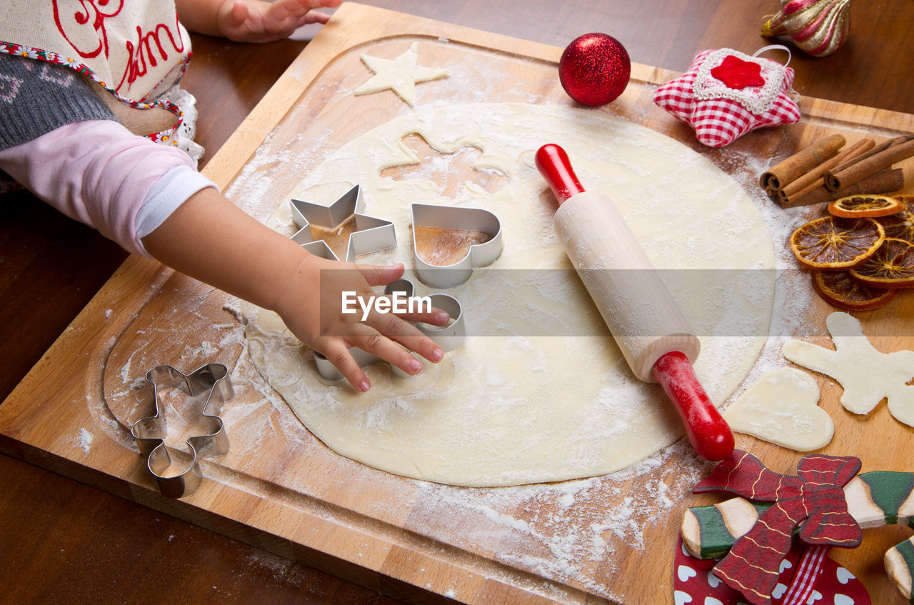 Cropped hand of child preparing cookies on table