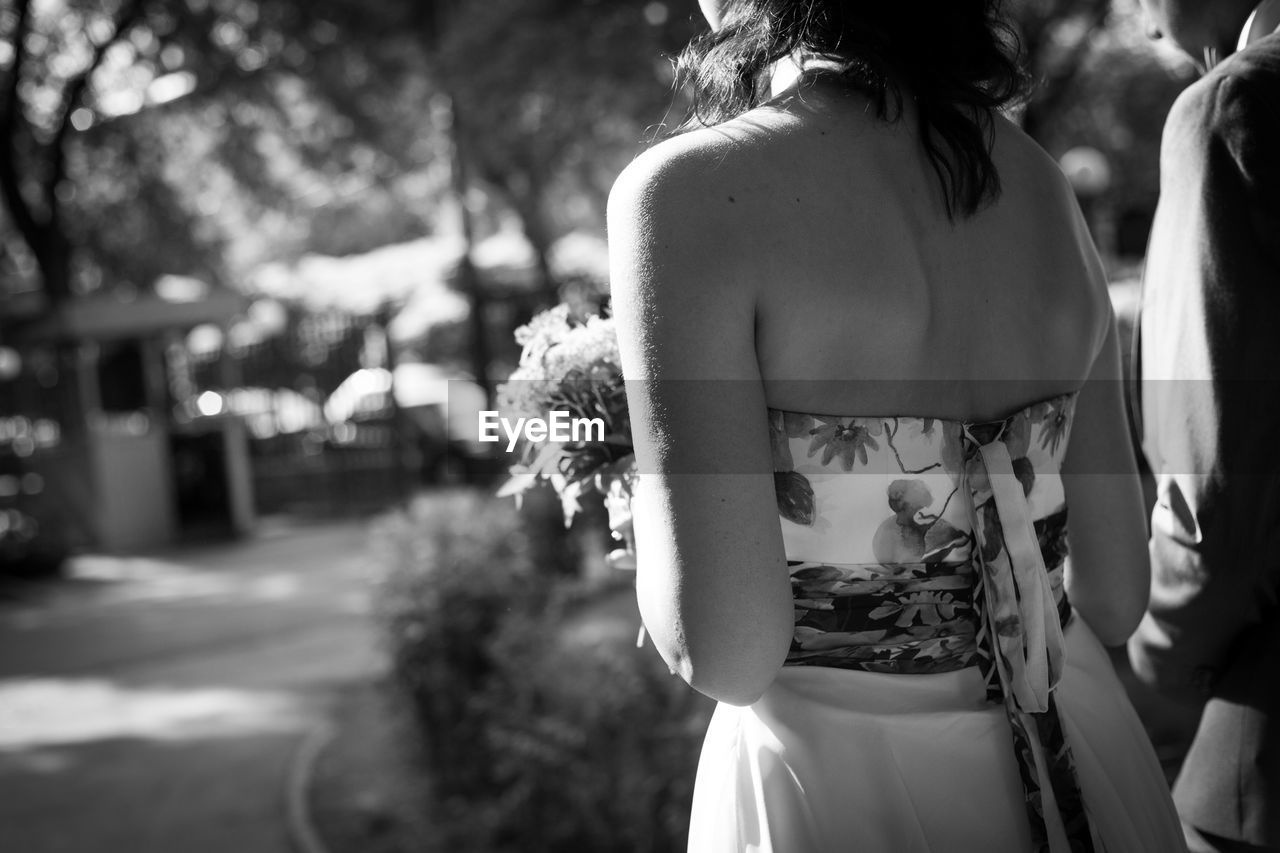 Rear midsection of bride and groom standing outdoors