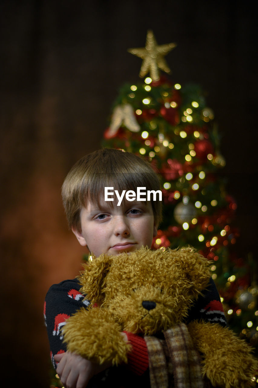 Portrait of boy with christmas tree at night
