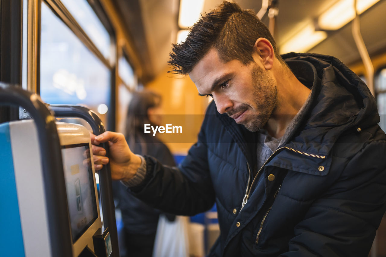 Smiling man buying ticket while commuting through tram