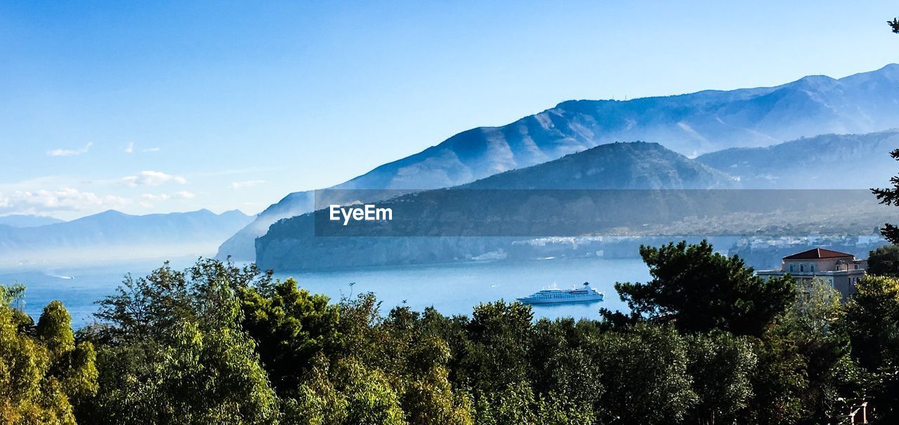 Scenic view of trees and mountains against blue sky