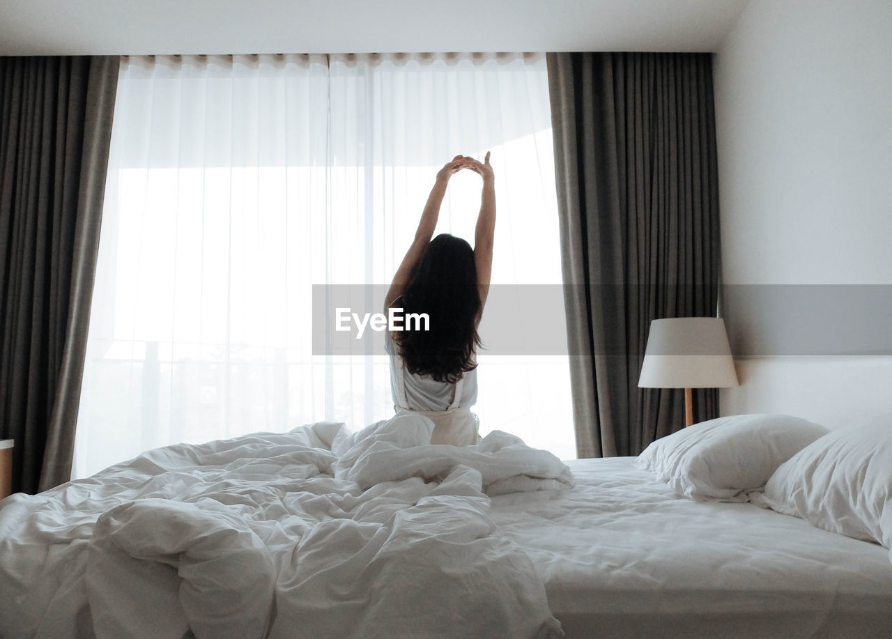 Rear view of woman relaxing on bed at home