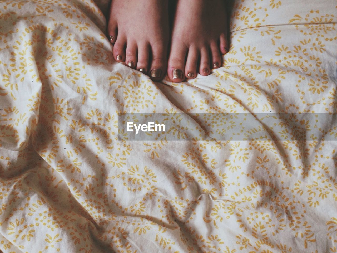 High angle view of woman feet on bed