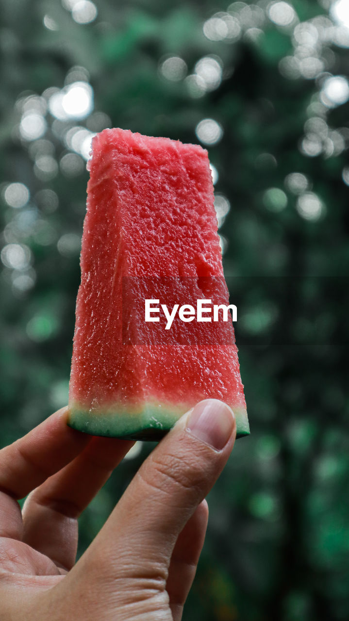 Close-up of hand holding ice cream cone . watermelon