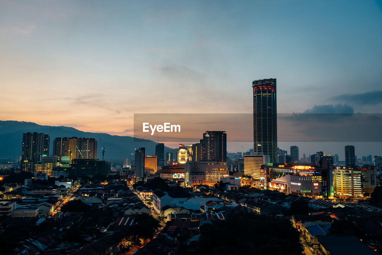 Illuminated buildings in city against sky during sunset