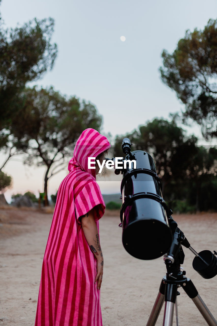 Rear view of woman looking through telescope