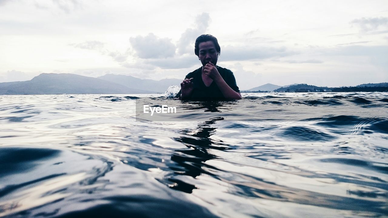 Young man in sea against sky