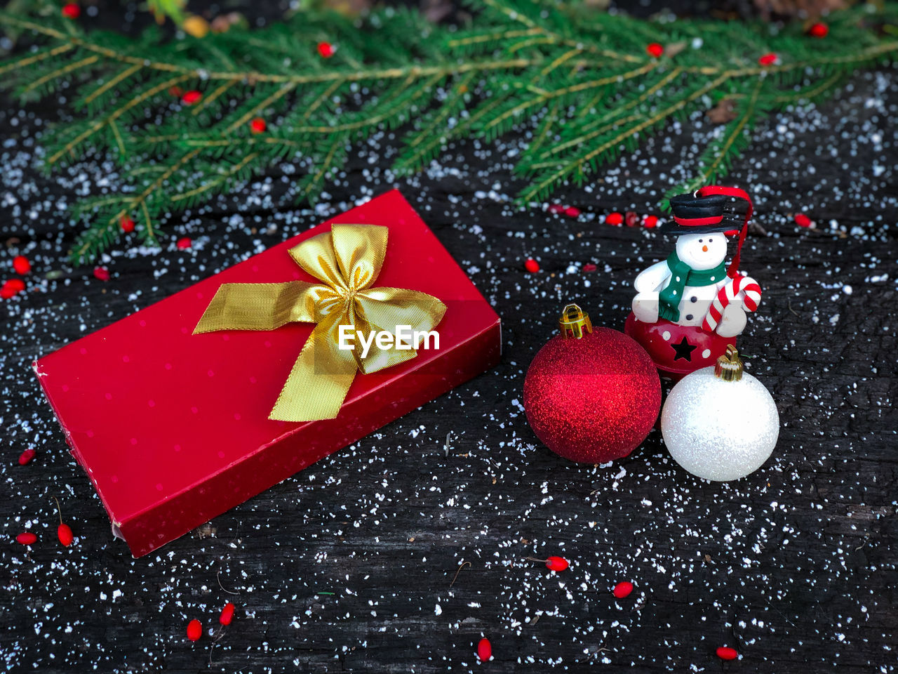 Red christmas gift and christmas baubles placed on a table decorated with fake snow