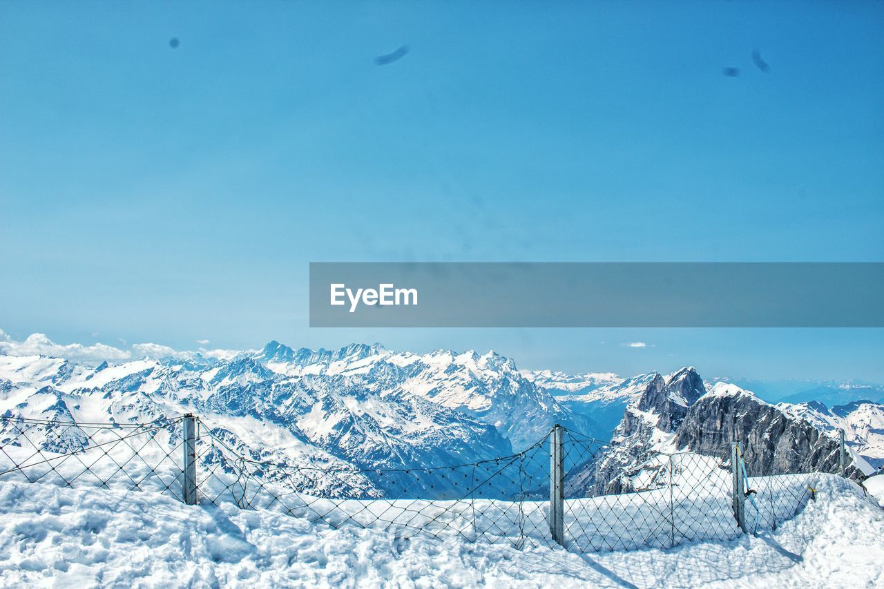 Scenic view of snowcapped mountains against blue sky