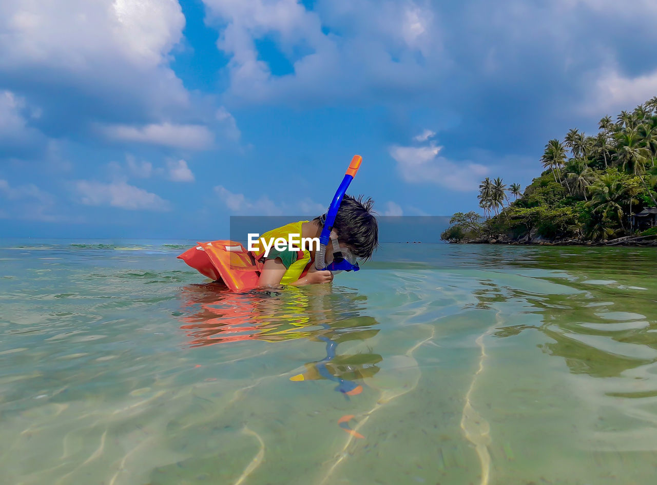 Boy in sea against sky