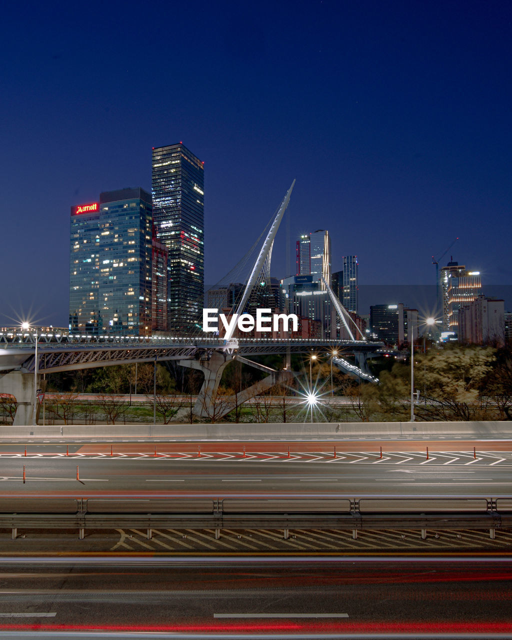 LIGHT TRAILS ON STREET AGAINST ILLUMINATED BUILDINGS IN CITY