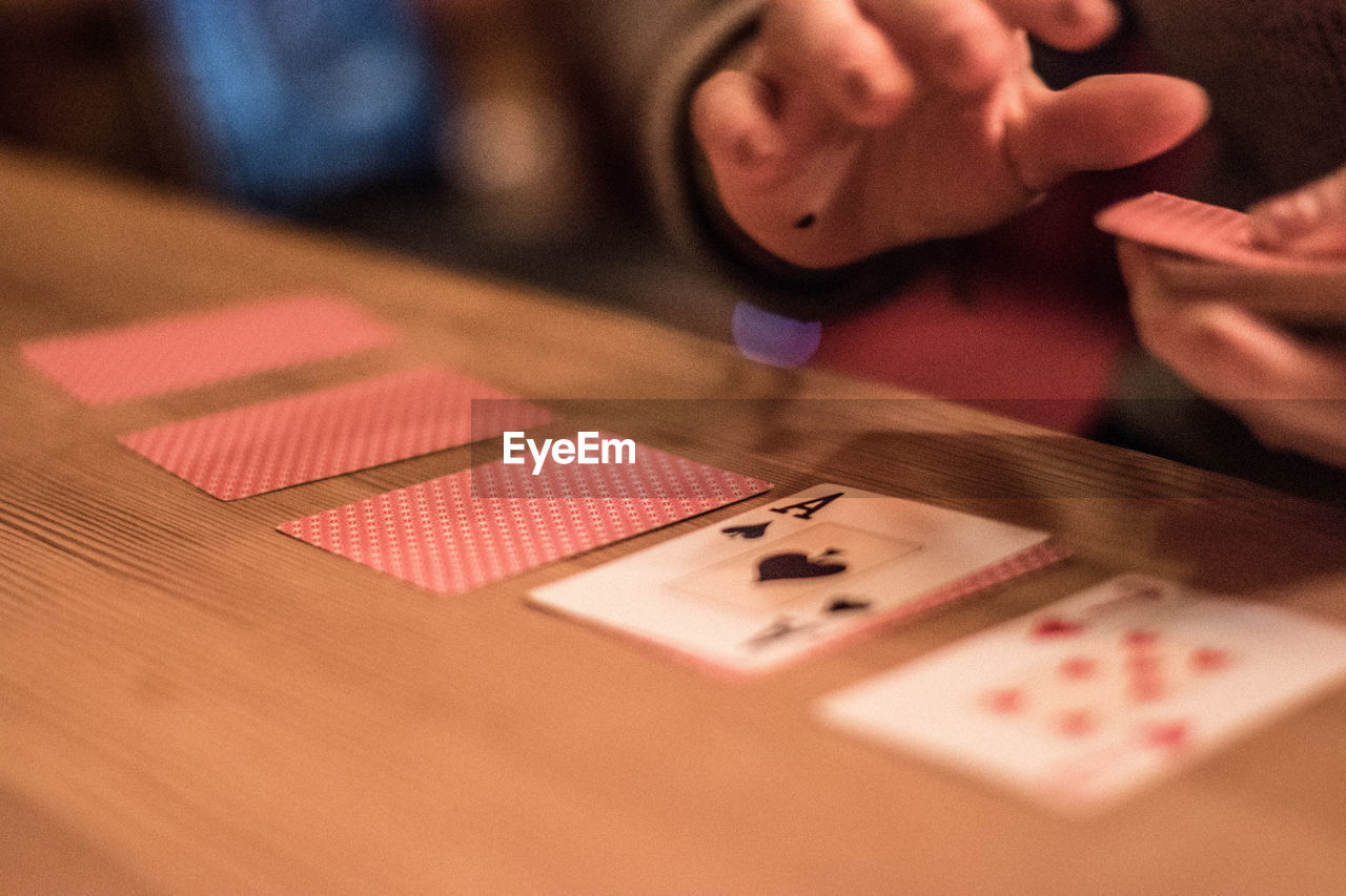 Close-up of hands holding playing cards on table
