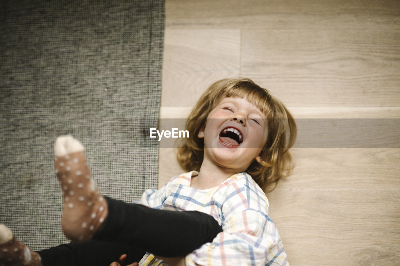 Directly above shot of cheerful girl lying down on floor at home