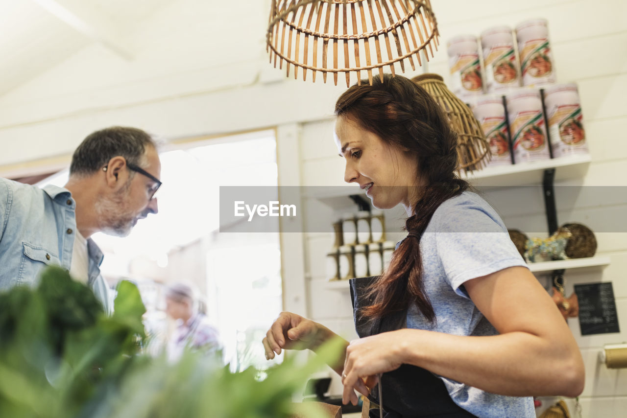 Low angle view of female clerk with mature customer at food store