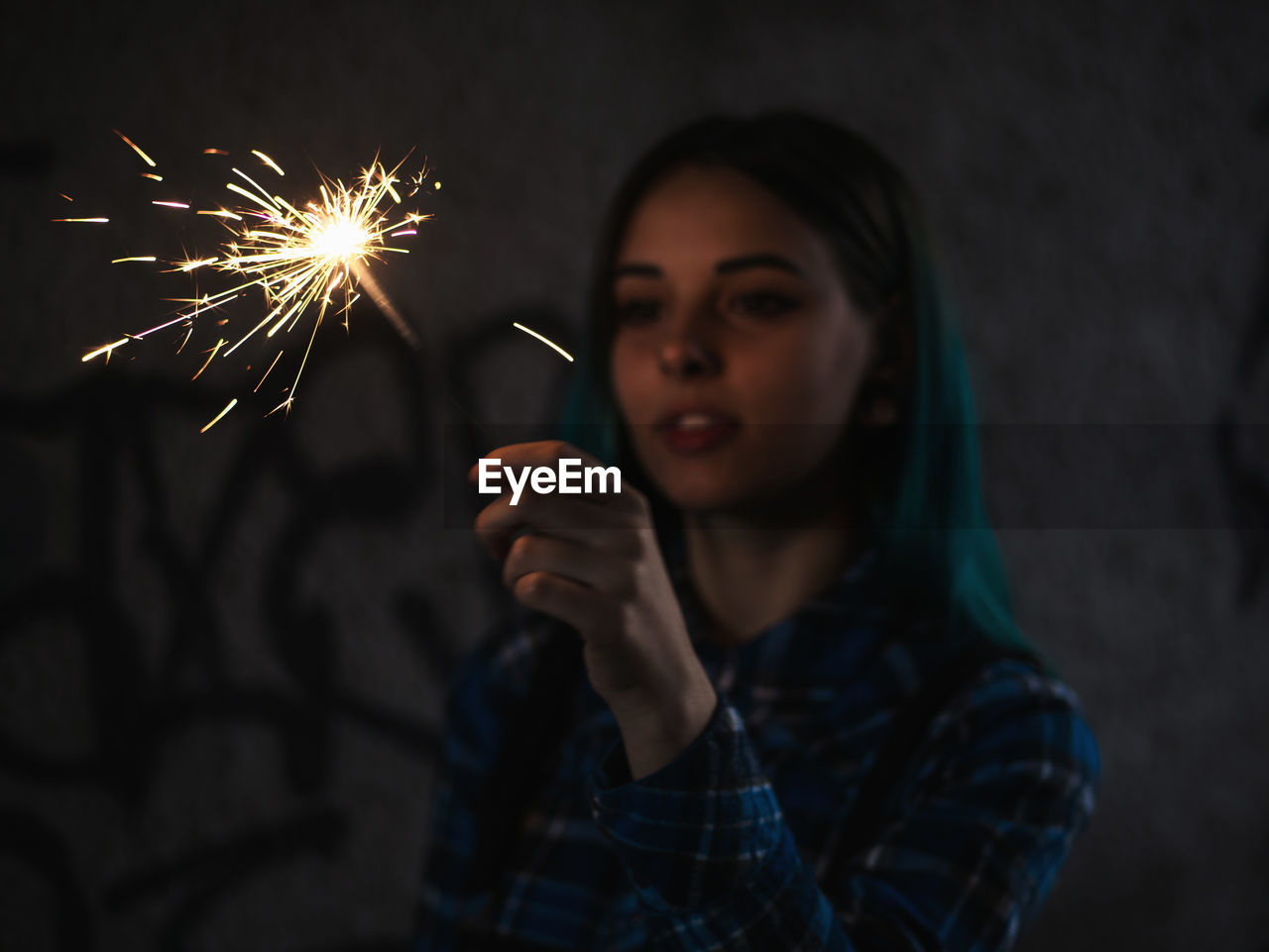 Close-up of young woman holding sparkler at night